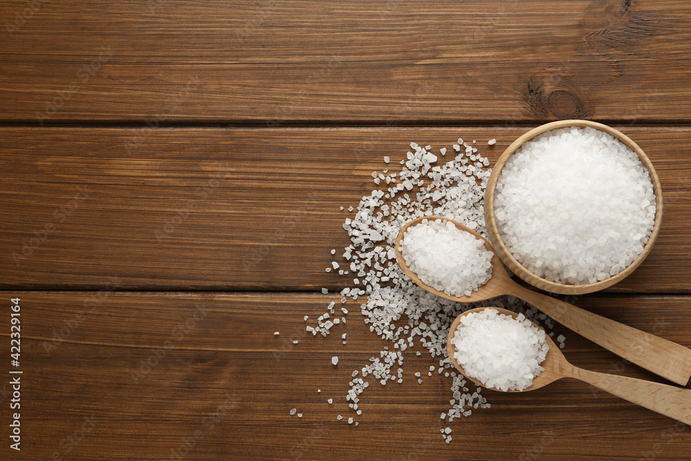 Natural sea salt on wooden table, flat lay. Space for text