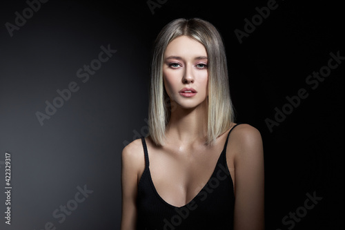 Woman with colored hair color of a blonde on black background. Coloring hair woman model in ash color. Portrait of a girl