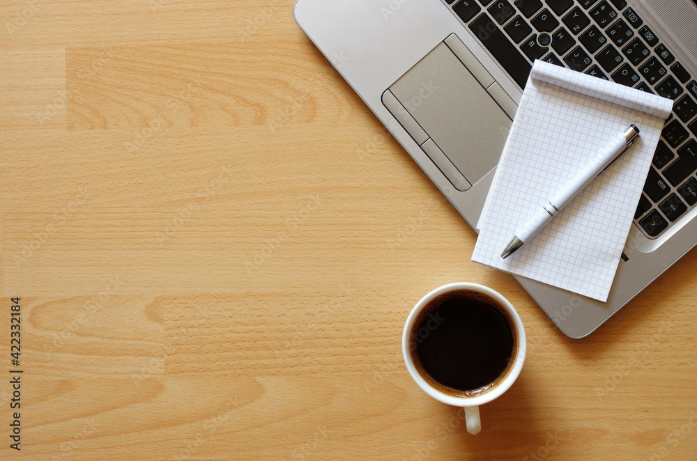 Laptop with coffee cup, notebook and pen on wooden background Top view. Concept for home office. Business concept. Work from home. Desk with laptop, blank notepad, coffee cup and pen on wooden table. Laptop with coffee cup, notebook and pen on wooden background Top view. Concept for home office. Business concept. Work from home. Desk with laptop, blank notepad, coffee cup and pen on wooden table.