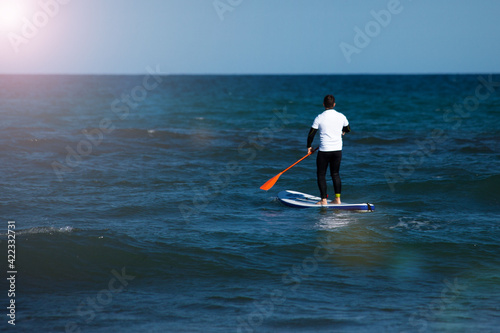 Man with surf board swimming in the sea. Water activity concept