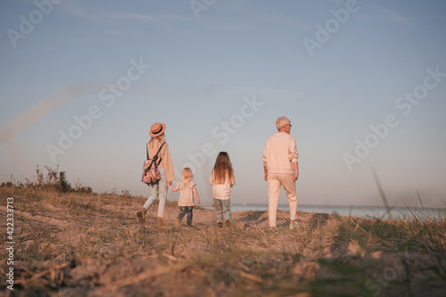 Young mother with daughters and grandmother walk along the shore