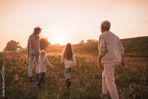 Young mother with daughters and grandmother walk together in the countryside