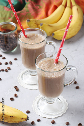 Banana latte with spices in two glass on gray background. Vertical format.