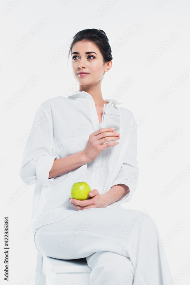 Young woman in white clothes holding fresh apple and glass of water isolated on white Young woman in white clothes holding fresh apple and glass of water isolated on white