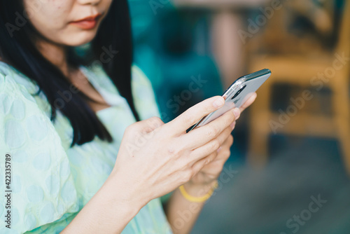 Women hand use smartphone with laptop background on table