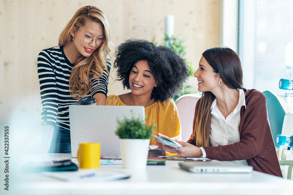 Casual multiethnic business women working with laptops while talking of they new projects together in coworking place.