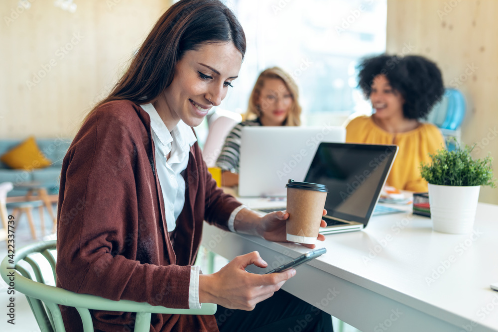 Casual multiethnic business women working with laptops while talking of they new projects together in coworking place. Casual multiethnic business women working with laptops while talking of they new projects together in coworking place.