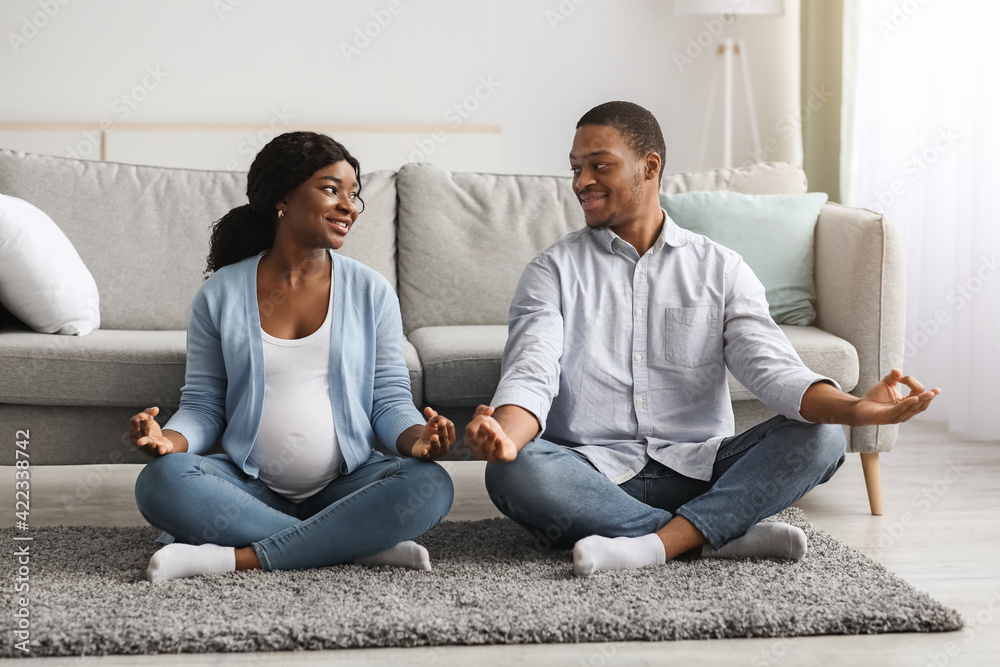Active pregnant black couple exercising at home, doing yoga Active pregnant black couple exercising at home, doing yoga