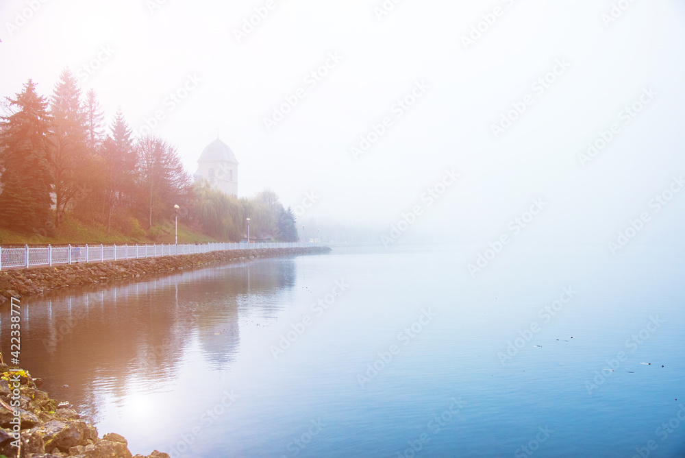mystical landscape with the old church above the lake in the misty morning in Ternopil, Ukraine