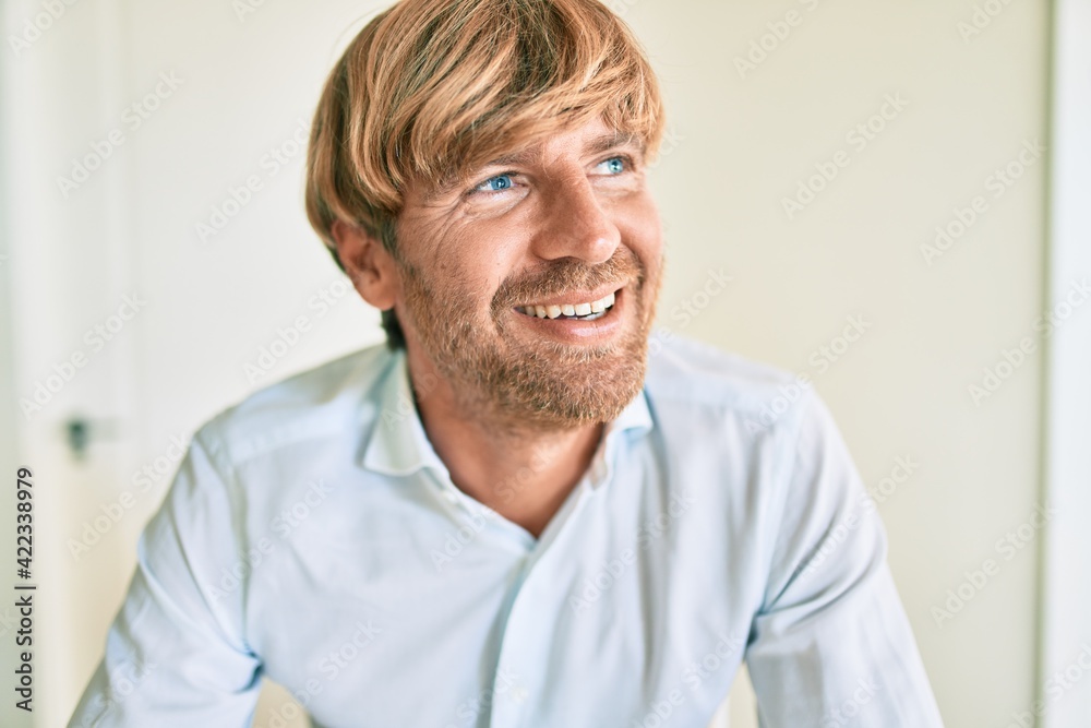 Young irish man smiling happy sitting on the table at home. Young irish man smiling happy sitting on the table at home.