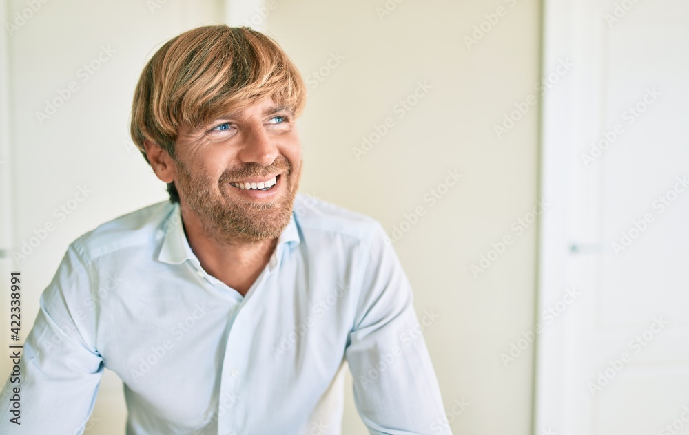 Obraz premium Young irish man smiling happy sitting on the table at home.