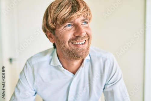Fototapeta Naklejka Na Ścianę i Meble -  Young irish man smiling happy sitting on the table at home.