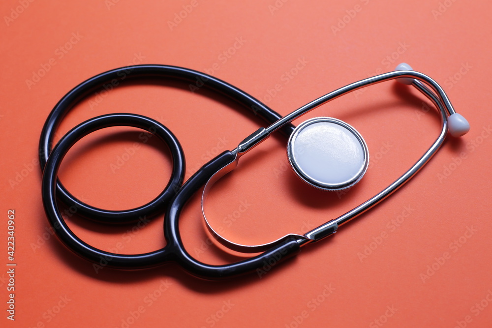 Blue medical stethoscope on orange background. Close-up Blue medical stethoscope on orange background. Close-up