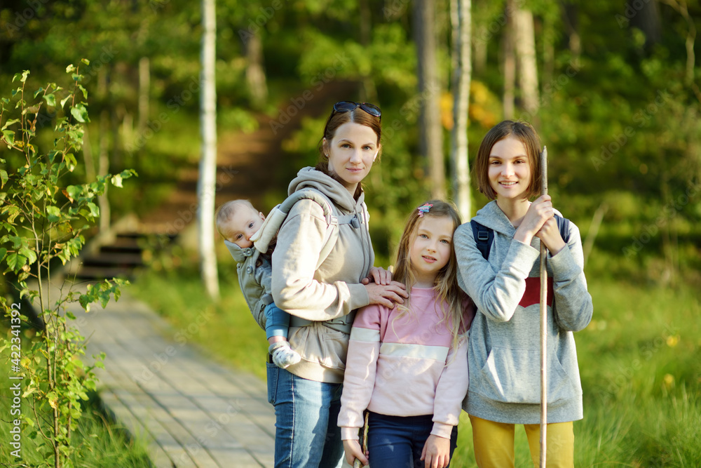 Family of four having fun during forest hike on beautiful summer day. Young mother and her three children exploring nature. Family of four having fun during forest hike on beautiful summer day. Young mother and her three children exploring nature.