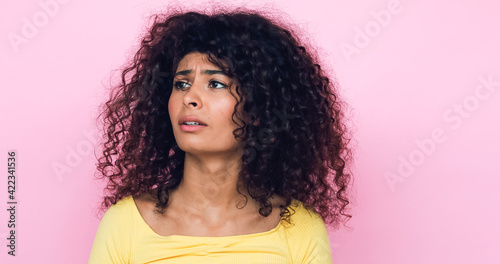 worried young woman looking away while thinking isolated on pink