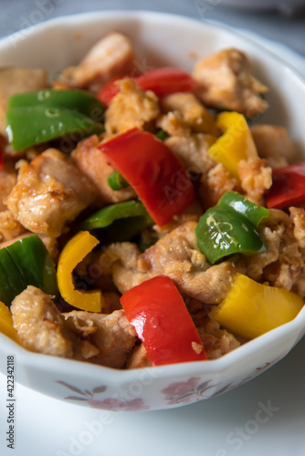 Chicken pieces and bell peppers in a bowl with use of selective focus.