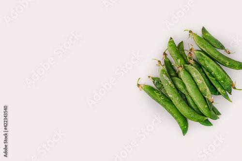 Fresh uncooked peas top view, with copy space against white background. Close up of closed whole green pod containers on a flat surface.