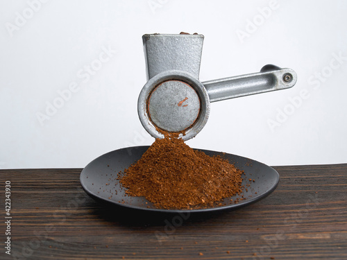 Vintage antique manual coffee grinder with roasted coffee beans, ground coffee on wooden table