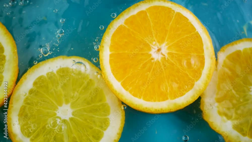 Fresh orange fruit slice fall down in water surface on blue green background. Splash and bubbles with drop water. Summer drink and food concept. Time to harvest Fresh orange fruit slice fall down in water surface on blue green background. Splash and bubbles with drop water. Summer drink and food concept. Time to harvest