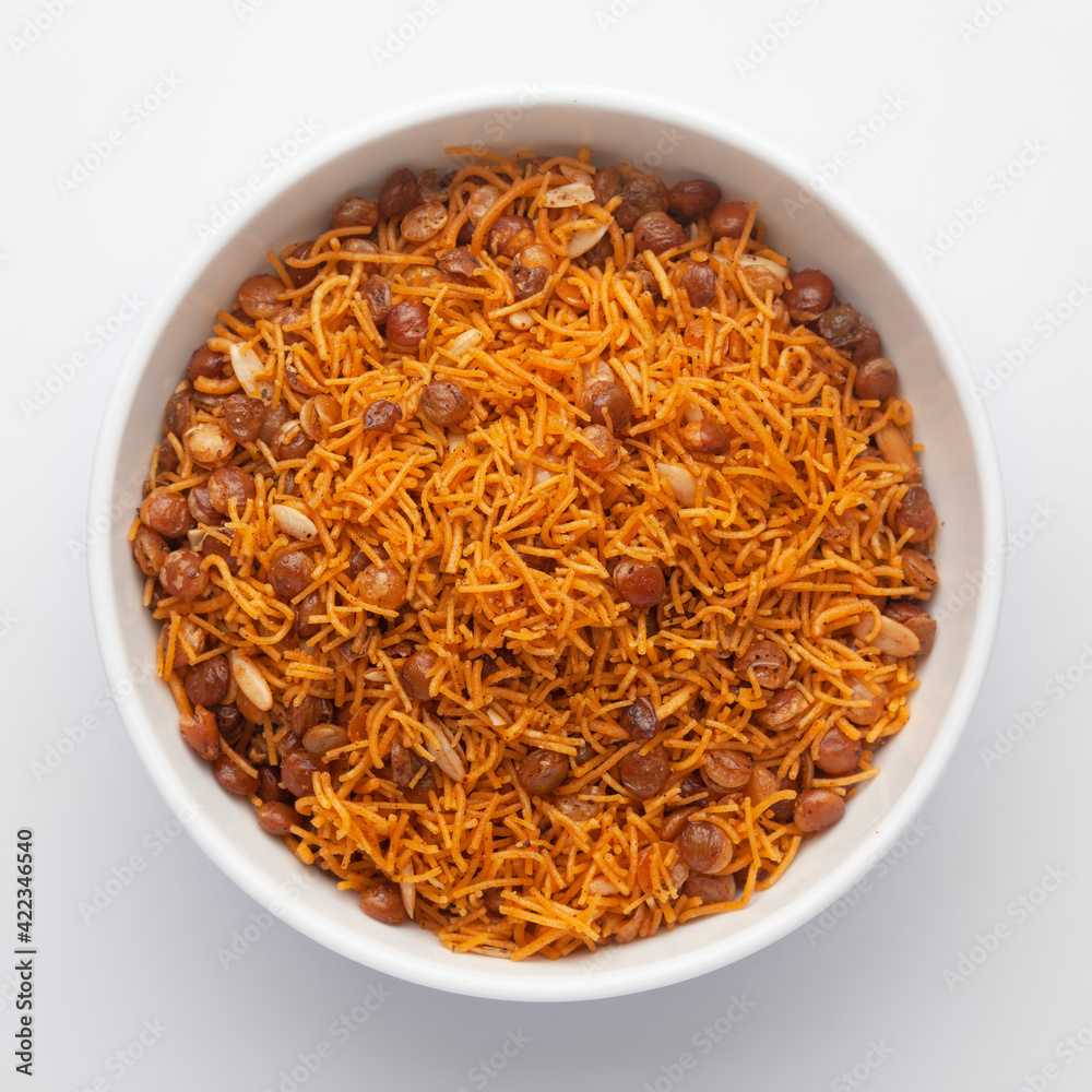 Close-Up Dal Bijli or Dal moth in a white ceramic bowl, made with roasted Masoor Dal (black lentils). Indian spicy snacks (Namkeen), Top View