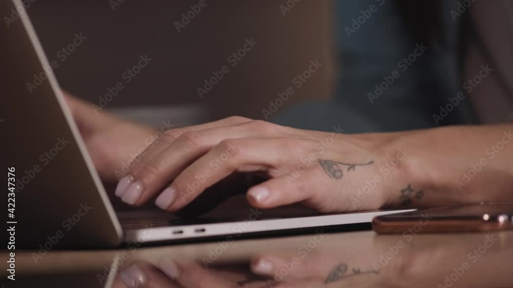 A cropped-view of a woman is using her laptop sitting at the table A cropped-view of a woman is using her laptop sitting at the table