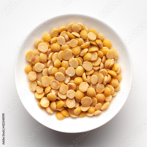 Macro Close-up of Organic arhar dal (Cajanus cajan) or split yellow dal inside a ceramic white bowl. Top view 