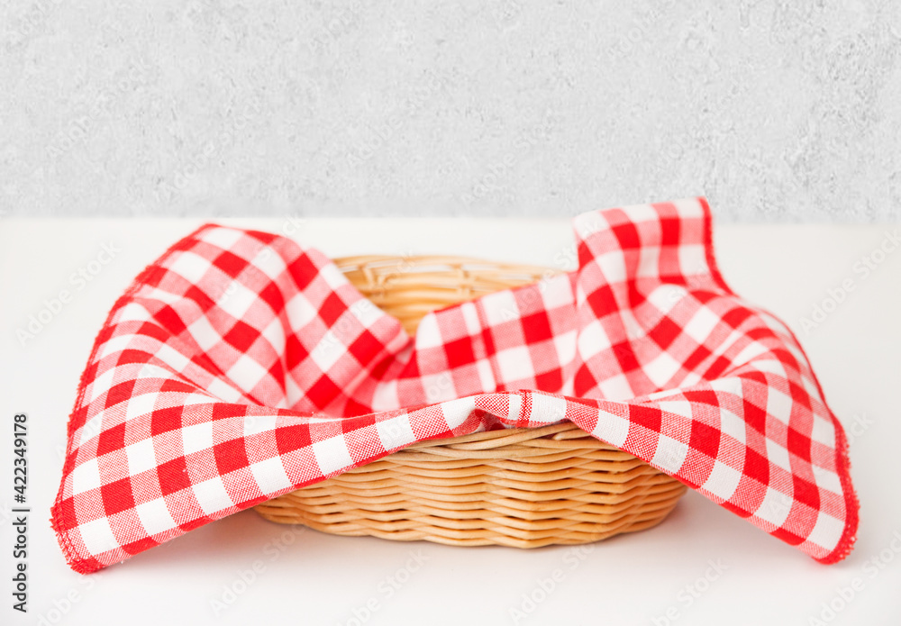 Red checkered tablecloth in a wicker basket on the table
Red checkered tablecloth in a wicker basket on the table