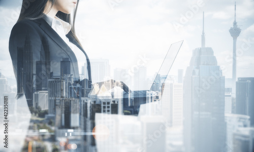 Business online concept with businesswoman with laptop on city skyscrapers background