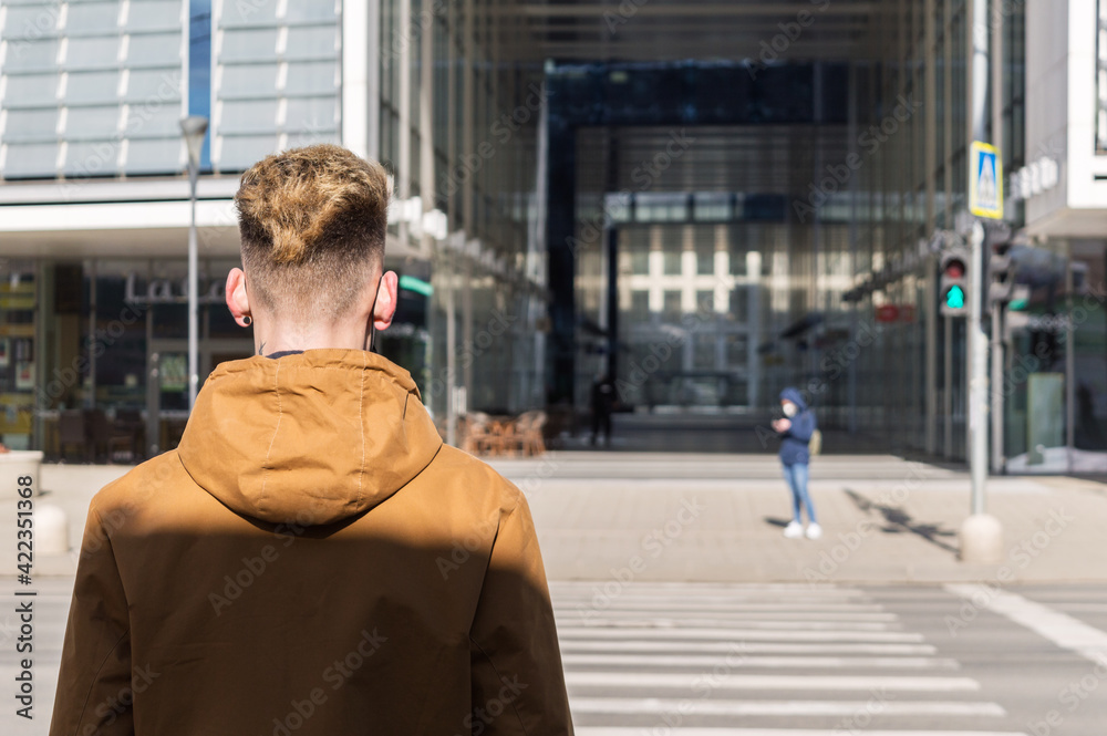 Young man wearing spring clothes on crosswalk.View from back Young man wearing spring clothes on crosswalk.View from back