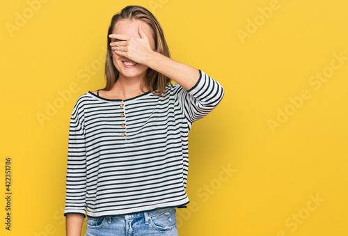 Beautiful blonde woman wearing casual clothes smiling and laughing with hand on face covering eyes for surprise. blind concept.
