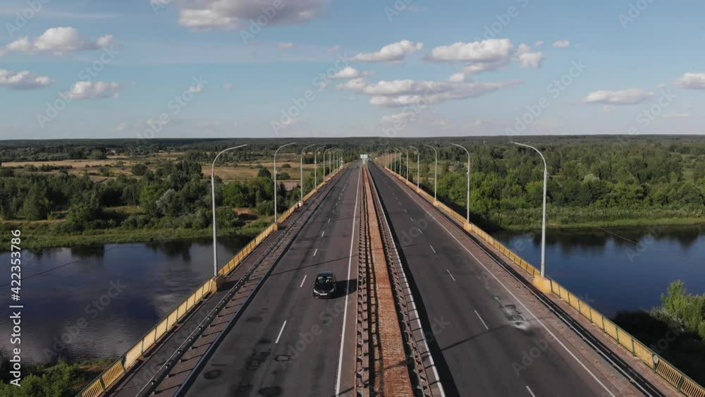 Drone shooting of a road bridge over a river with traffic and city panoramas against a blue sky on a summer day Drone shooting of a road bridge over a river with traffic and city panoramas against a blue sky on a summer day