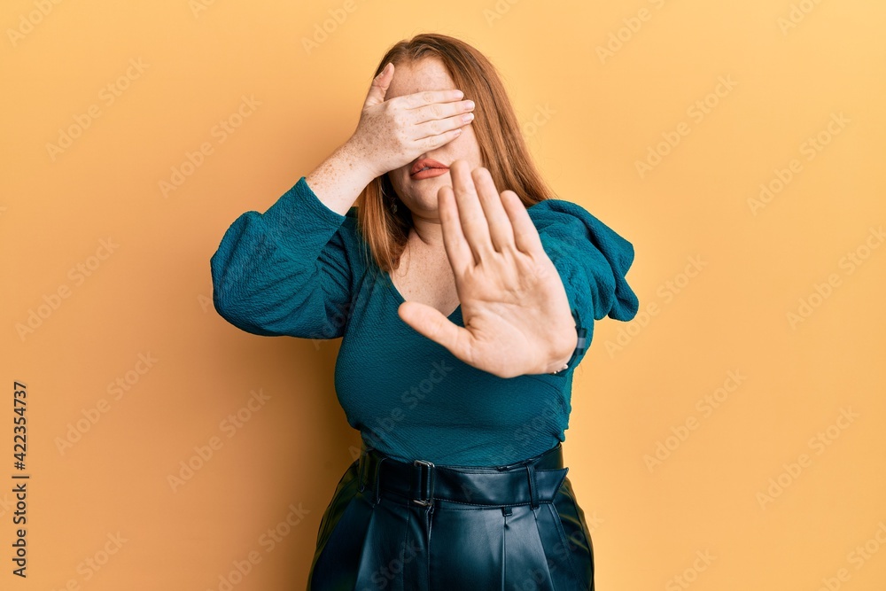 Young beautiful redhead woman wearing elegant and sexy look covering eyes with hands and doing stop gesture with sad and fear expression. embarrassed and negative concept. Young beautiful redhead woman wearing elegant and sexy look covering eyes with hands and doing stop gesture with sad and fear expression. embarrassed and negative concept.