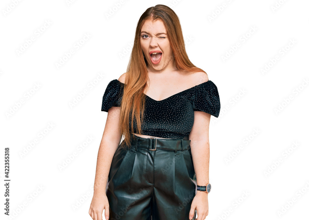 Young beautiful redhead woman wearing elegant clothes winking looking at the camera with sexy expression, cheerful and happy face. Young beautiful redhead woman wearing elegant clothes winking looking at the camera with sexy expression, cheerful and happy face.
