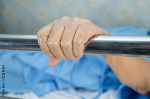 Asian senior or elderly old woman patient lie down handle the rail bed with hope on a bed in the hospital.