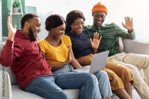 Group of black friends sitting on couch, having video call