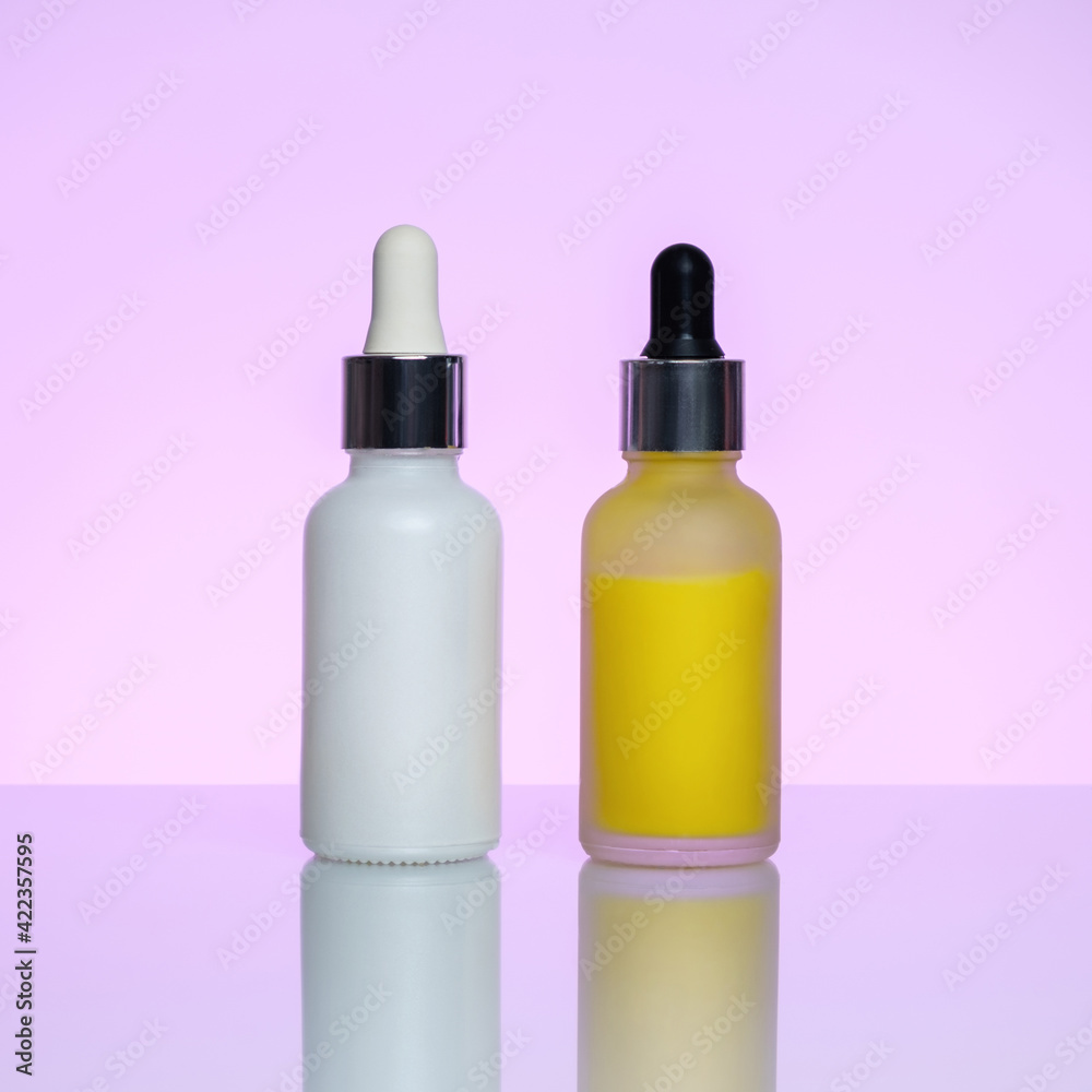 Bottles of serum on a light pink background. Moisturizer, vitamin C, hyaluronic acid. Bottles of serum on a light pink background. Moisturizer, vitamin C, hyaluronic acid.