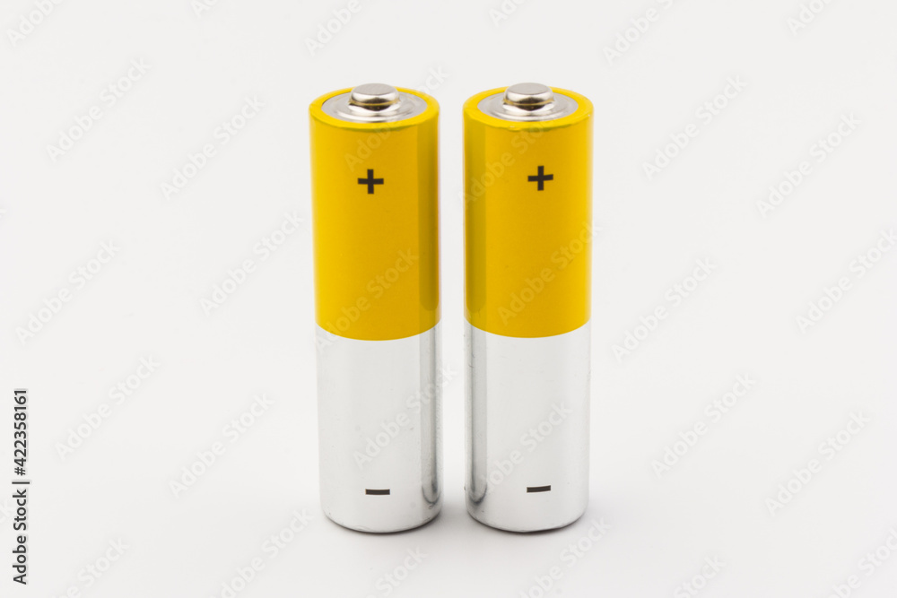 Photo of gray-yellow alkaline AA batteries on white background. Recycling of rechargeable NiMH batteries. The most popular size of accumulators. Copy space. Photo of gray-yellow alkaline AA batteries on white background. Recycling of rechargeable NiMH batteries. The most popular size of accumulators. Copy space.