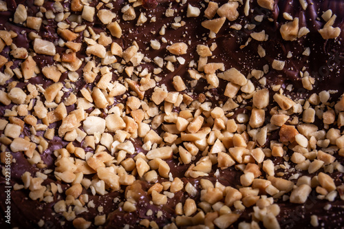 Stuffed chocolate easter egg with peanut and caramel on a wooden table with lots of peanuts around. Close up.