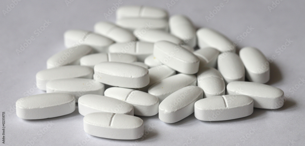 White, oblong pills poured from a bottle on a white background. with copy space, shallow depth of field. Medicine concept White, oblong pills poured from a bottle on a white background. with copy space, shallow depth of field. Medicine concept