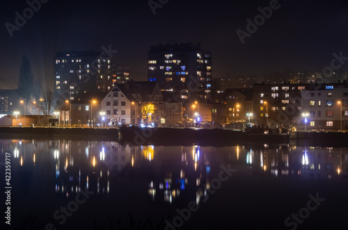 ship by the illuminated wharf with buildings and skyscrapers at night