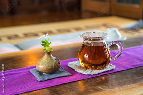 Hot tea and flower in vase on wooden table
