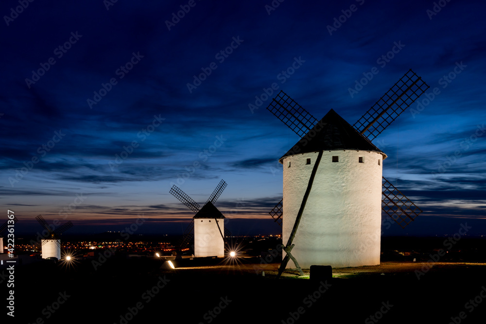 view of the historic white windmills of La Mancha above the town of Campo de Criptana at sunset