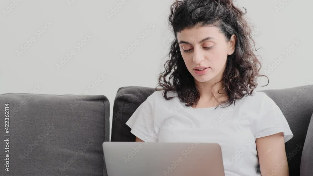 A beautiful young woman is using her laptop computer sitting on the couch at home A beautiful young woman is using her laptop computer sitting on the couch at home