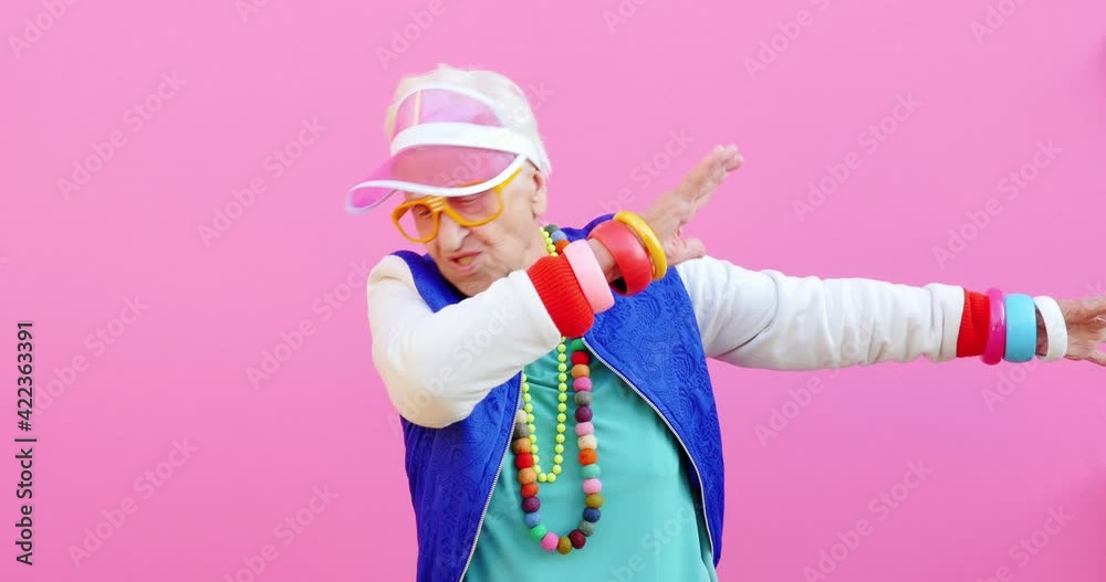 Footage of a funny grandmother with fashionable look acting on colored backgrounds