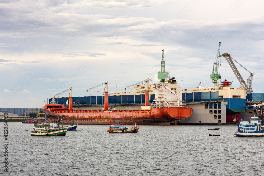 Large general cargo ship for transportation import export goods moored in the harbor and in the process of loading and unloading or conveying products