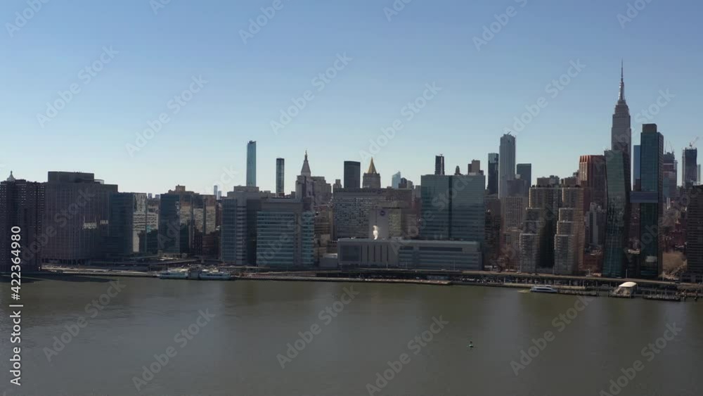An aerial view over a calm East River on a sunny day with blue skies. The camera facing midtown Manhattan pan left slowly. An aerial view over a calm East River on a sunny day with blue skies. The camera facing midtown Manhattan pan left slowly.