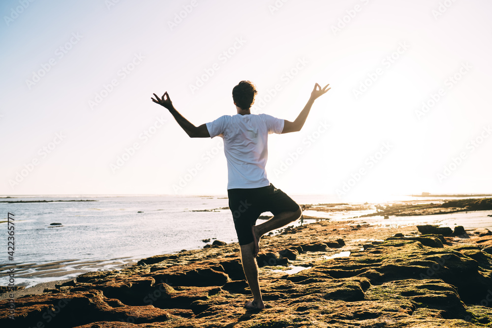 Anonymous man practicing yoga on seashore Anonymous man practicing yoga on seashore