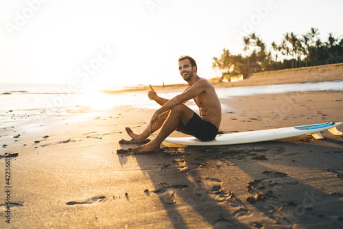 Photography Portrait of cheerful surfer guy posing at professional surfboard enjoying sporti