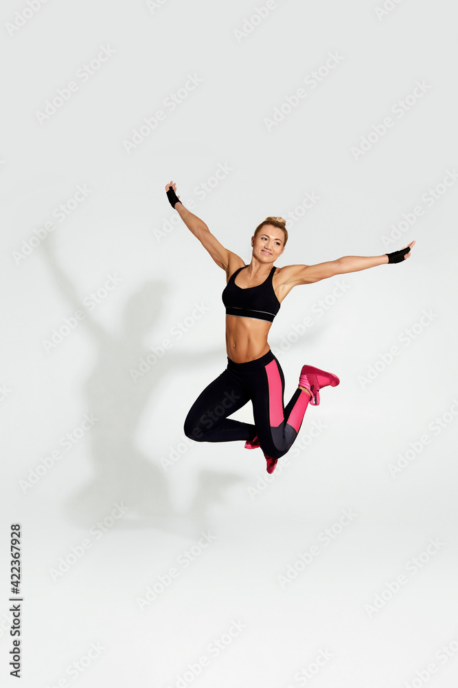 athletic blonde woman in black sportswear jumping
