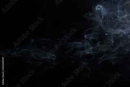 Abstract wisps of smoke on a black background.